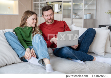 Cheerful couple looking into web camera of laptop computer, having video call with friends, parents  133028889