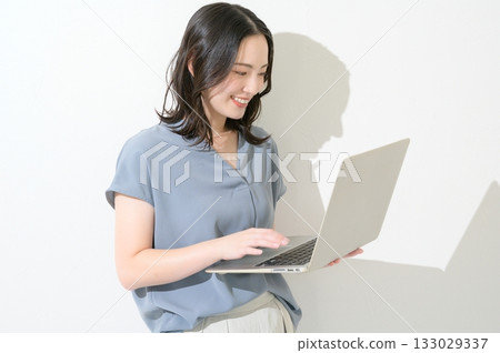一位日本女性在白色背景下拿著筆記型電腦。 133029337