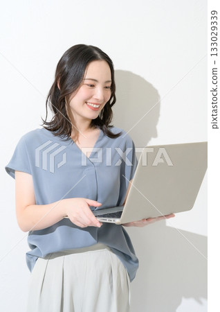 Japanese woman holding a laptop on a white background Japanese woman holding a laptop on a white background 133029339