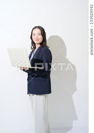 一位日本女性在白色背景下拿著筆記型電腦。 133029342