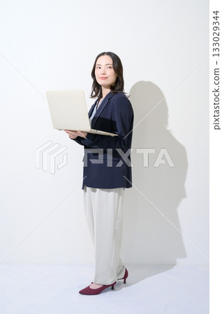 一位日本女性在白色背景下拿著筆記型電腦。 133029344