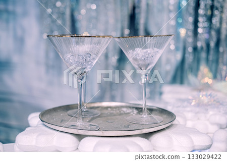 Two elegant martini glasses with crushed ice on a silver tray in a festive winter-themed setting. Holiday celebration styling, Christmas entertaining, minimal luxury decor, frosted seasonal aesthetic Two elegant martini glasses with crushed ice on a silver tray in a festive winter-themed setting. Holiday celebration styling, Christmas entertaining, minimal luxury decor, frosted seasonal aesthetic 133029422