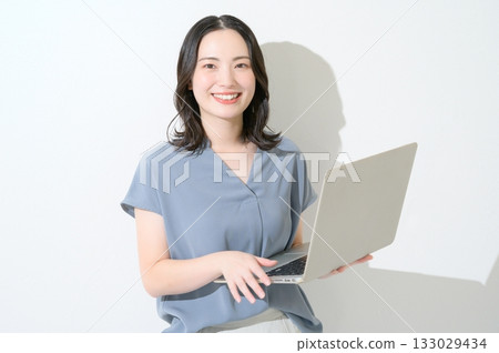 Japanese woman looking at the camera with a laptop on a white background Japanese woman looking at the camera with a laptop on a white background 133029434
