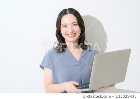 Japanese woman looking at the camera with a laptop on a white background Japanese woman looking at the camera with a laptop on a white background 133029435