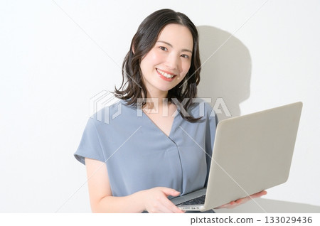 Japanese woman looking at the camera with a laptop on a white background Japanese woman looking at the camera with a laptop on a white background 133029436