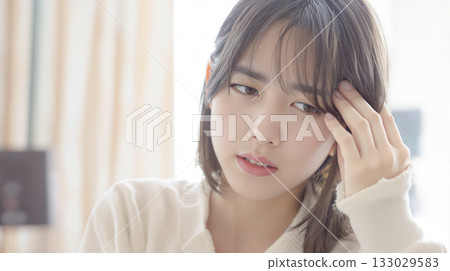 一名年輕女子似乎很痛苦，一隻手放在頭上 133029583