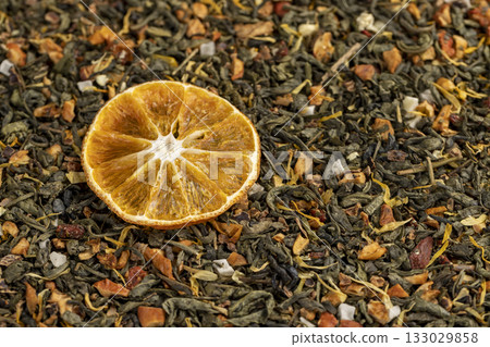 large-leaf green tea with flavorings and pieces of fruit and cut dried oranges, bright large dry orange slices and green tea with pieces of fruit and berries 133029858