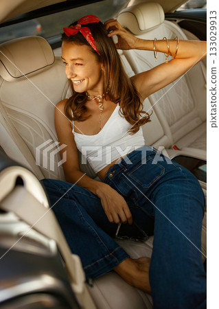 Woman with feet on dashboard enjoying sunset through window 133029913