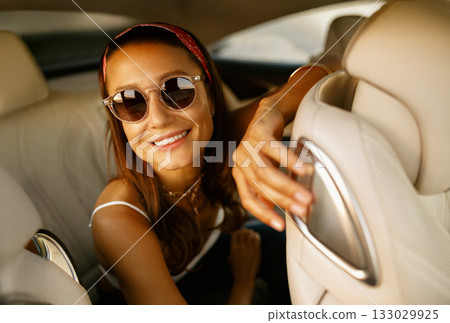 Woman in bandana enjoying warm sunlight during road trip relaxation 133029925