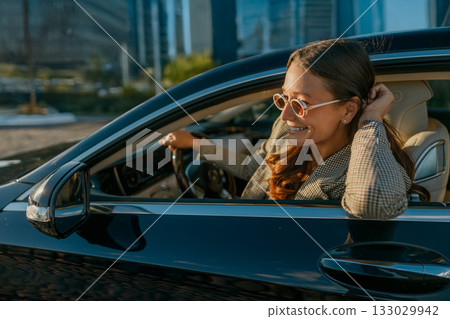 Ambitious woman by car window strategizes next steps confidently Ambitious woman by car window strategizes next steps confidently 133029942