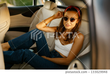 Serene female figure lounges with legs elevated in sunlit automobile 133029948