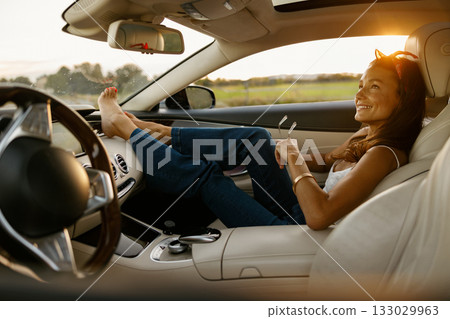 Gentle woman enjoying quiet moment inside her car during beautiful sunset Gentle woman enjoying quiet moment inside her car during beautiful sunset 133029963