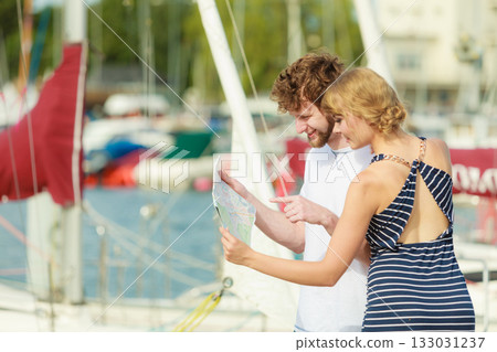 Tourist couple in marina looking up directions on map 133031237