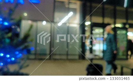 A girl walks along an evening street decorated for Christmas. Blurred. Along the storefronts of trendy shops and a cinema along evening street in blurred focus. Before Christmas 133031465