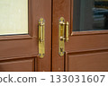 Close-up of old brass door handles with patina on a brown wooden front door. Vintage background for the concept of entrance, security, opportunity, and decision making for the future. 133031607