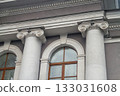Facade fragment of an old classicism style building with Ionic columns and an arched window. Architectural background symbolizing justice, government, education, or culture and finance. 133031608
