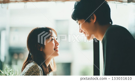 情侶在咖啡館裡深情對望，在自然光下微笑。 133031610