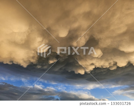 Storm clouds on sunset. Light in the dark and dramatic storm clouds. Background of storm clouds before a thunderstorm. Mammatus clouds Storm clouds on sunset. Light in the dark and dramatic storm clouds. Background of storm clouds before a thunderstorm. Mammatus clouds 133031726