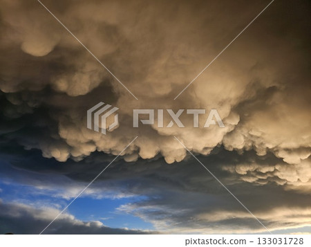 Storm clouds on sunset. Light in the dark and dramatic storm clouds. Background of storm clouds before a thunderstorm. Mammatus clouds Storm clouds on sunset. Light in the dark and dramatic storm clouds. Background of storm clouds before a thunderstorm. Mammatus clouds 133031728