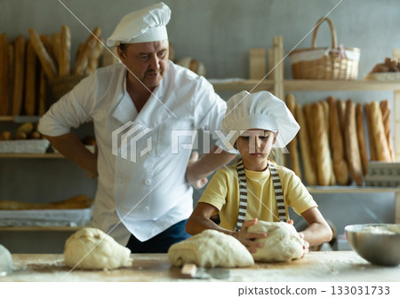 Little daughter and father make dough together in bakery kitchen 133031733
