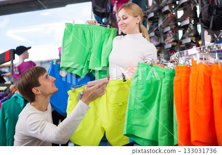 Husband and wife choose summer shorts together in clothing store Husband and wife choose summer shorts together in clothing store 133031736