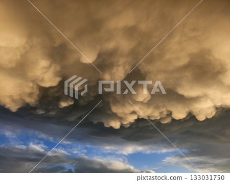 Storm clouds on sunset. Light in the dark and dramatic storm clouds. Background of storm clouds before a thunderstorm. Mammatus clouds Storm clouds on sunset. Light in the dark and dramatic storm clouds. Background of storm clouds before a thunderstorm. Mammatus clouds 133031750