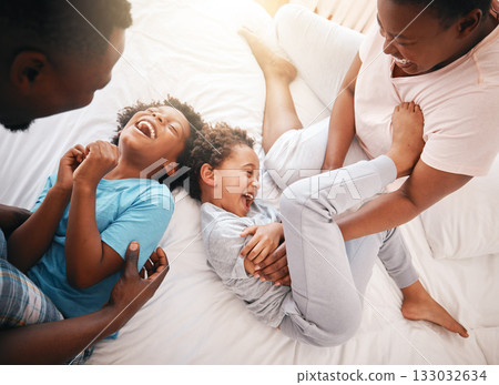 Tickle, funny and relax with black family in bedroom for bonding, playful and affectionate. Laugh, happiness and crazy with parents playing with children at home for wake up, morning and silly 133032634