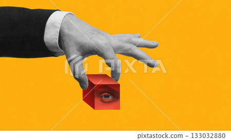 Abstract artwork. Hand holding red cube with hidden eye inside on yellow background Abstract artwork. Hand holding red cube with hidden eye inside on yellow background 133032880
