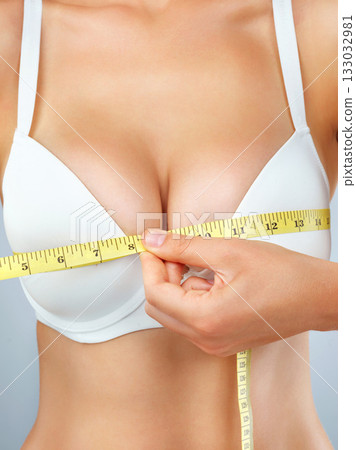 Woman, hand and breast augmentation with measuring tape, bust size with body and lose weight on studio background. Female person in underwear, bra and chest measurement, health and plastic surgery 133032981