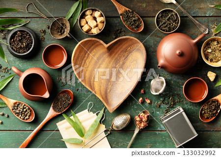 Heart-Shaped Bowl with Teaware and Tea Leaves on Rustic Background 133032992