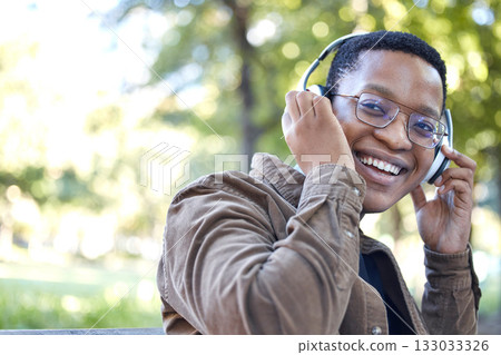 Headphones, park and portrait of african man listening to music for outdoor, mental health and relaxing break in nature. Young, happy student or black person with audio technology in garden or campus 133033326