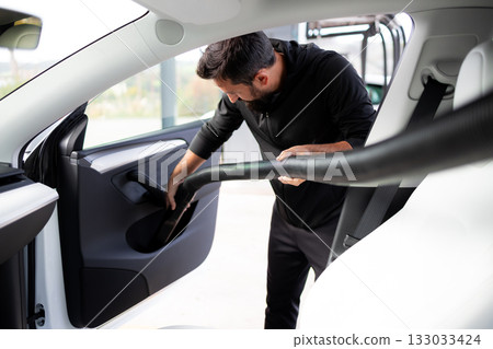 Adult caucasian male vacuuming car interior at a car wash station 133033424
