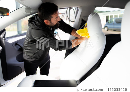 Adult male cleaning car interior with yellow cloth 133033426