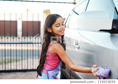Washing car, happy and child with water, home chores and cleaning. Smile, routine and a little girl with happiness while learning to clean transport in the driveway for polishing with responsibility Washing car, happy and child with water, home chores and cleaning. Smile, routine and a little girl with happiness while learning to clean transport in the driveway for polishing with responsibility 133033659