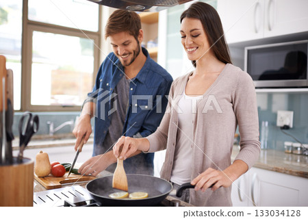 Happy couple, food and cooking together in the kitchen on pan with healthy organic nutrition or diet for dinner at home. Man helping woman with smile in happiness making meal with vegetables on stove 133034128