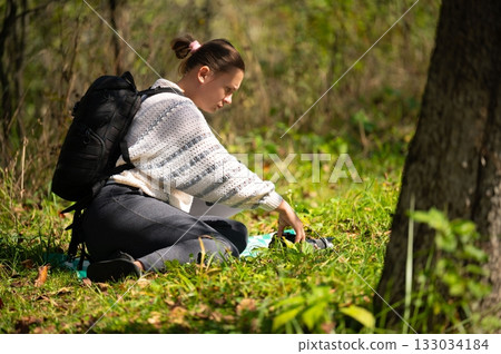Photographer in nature, capturing the essence of the natural world through her camera lens amidst a tranquil forest setting 133034184