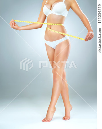 Woman in underwear, body and measuring tape, lose weight and fitness with abdomen isolated on studio background. Female person, waist measurement and diet with health, weightloss and exercise 133034259
