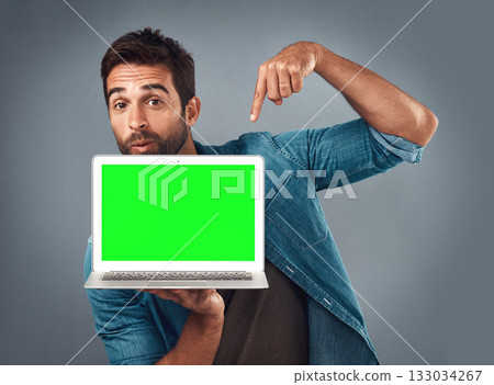 Man, laptop and pointing on mockup green screen for advertising or marketing against a grey studio background. Portrait of male person showing computer display, chromakey or mock up for advertisement Man, laptop and pointing on mockup green screen for advertising or marketing against a grey studio background. Portrait of male person showing computer display, chromakey or mock up for advertisement 133034267