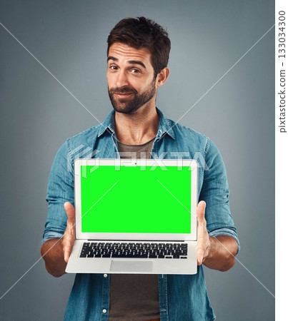 Man, laptop and portrait with mockup green screen for advertising or marketing against a grey studio background. Male person showing computer display, chromakey or mock up space for advertisement 133034300