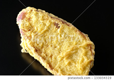Sweet potato tempura photographed alone against a black background Sweet potato tempura photographed alone against a black background 133034319
