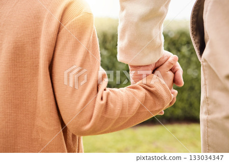 Kid, park and holding hands with parents on vacation, adventure walk or freedom in nature together. Young child child, outdoor happiness or holiday for helping hand, support and walking in sunshine 133034347