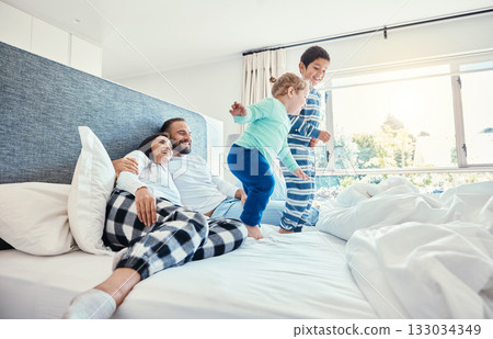 Family, morning and kids jumping on a bed, playing while having fun in the bedroom of their parents. Happy, children or wake up with a brother and sister in a house feeling playful or excited 133034349