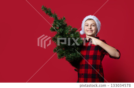 Cheerful boy in Santa hat and red plaid shirt holding thumbs up, sign of approval like Cheerful boy in Santa hat and red plaid shirt holding thumbs up, sign of approval like 133034578