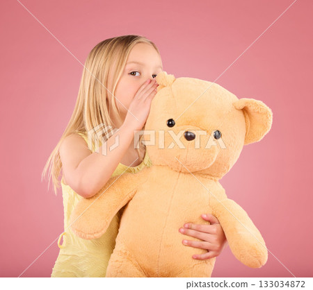 Teddy, secret and young girl talking and whispering to a toy bear in a studio. Playing, child and bonding with love and care for toys with isolated pink background in a happy discussion together Teddy, secret and young girl talking and whispering to a toy bear in a studio. Playing, child and bonding with love and care for toys with isolated pink background in a happy discussion together 133034872