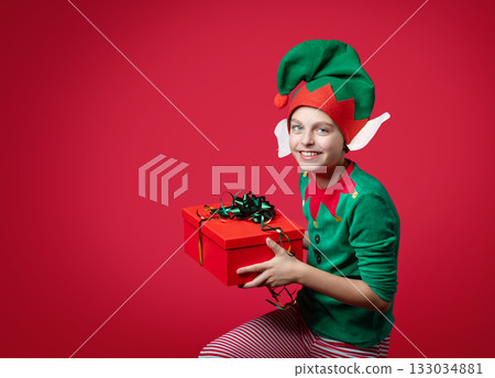 Merry Christmas concept. Smiling funny boy in Santa's elf costume holding Merry Christmas concept. Smiling funny boy in Santa's elf costume holding 133034881