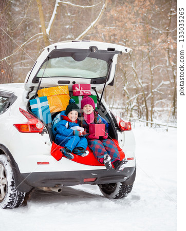 Merry Christmas. Happy New Year. Happy family children sitting in car loaded with boxes of gifts and Christmas tree against the background 133035265