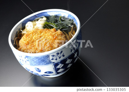 Kakesoba noodles with croquettes photographed against a black background Kakesoba noodles with croquettes photographed against a black background 133035305