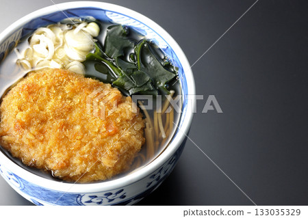 Kakesoba noodles with croquettes photographed against a black background 133035329