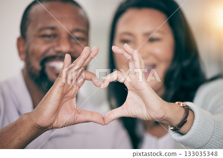 Hands, love and heart with a couple in their home to relax together in the living room closeup. Hand gesture, emoji or romance with a senior man and woman bonding while sitting in their house 133035348