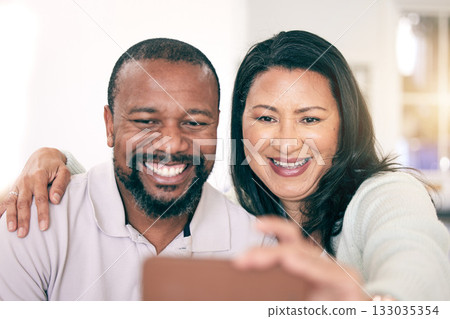 Selfie, interracial and couple with a hug for bonding, memory together or quality time. Smile, embrace and mature man and woman smiling for a picture for social media, love or happiness at home 133035354